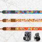 Colorful camera straps with various patterns and names on a marble surface.