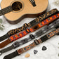 Guitar straps with various patterns on a marble surface with a guitar.