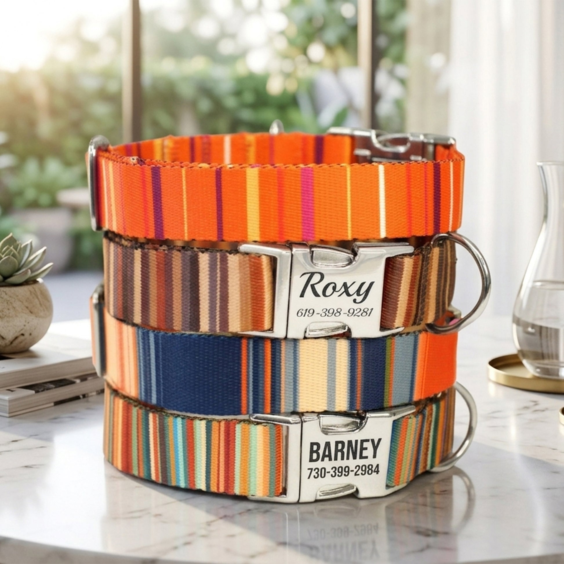 Stack of colorful striped dog collars with engraved names and phone numbers on a marble surface.