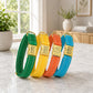 Four colorful dog collars with gold buckles on a marble surface.