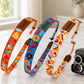Three colorful camera straps with different patterns on a marble surface.