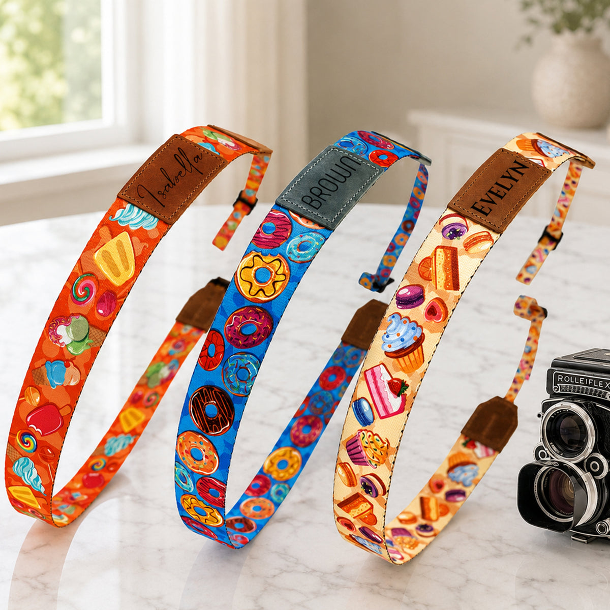 Three colorful camera straps with different patterns on a marble surface.
