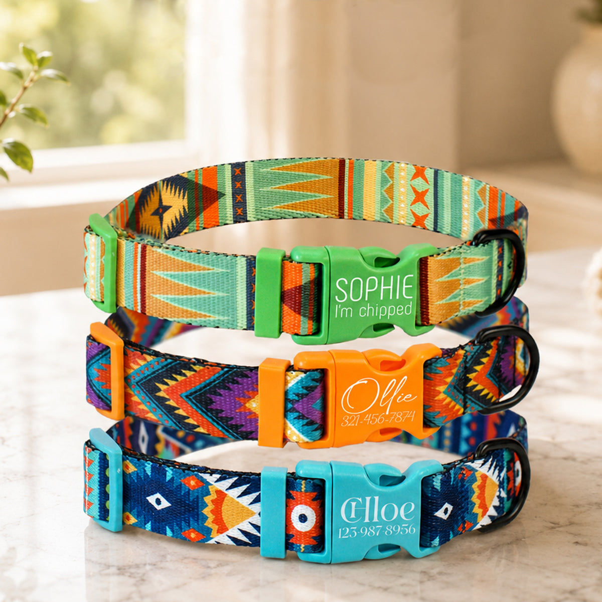Three colorful dog collars with personalized engraved names on a light surface.