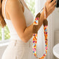 Person holding a camera with a colorful strap featuring heart designs.