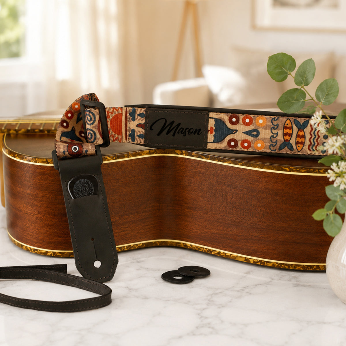 Guitar with a colorful strap on a marble surface, with a blurred indoor background.