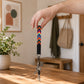 Hand holding a colorful keychain with keys on a wooden surface, with a blurred indoor background.
