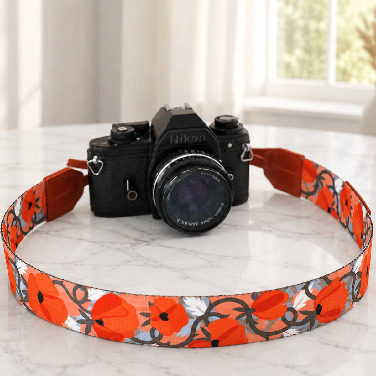 Camera with a floral strap on a marble surface