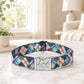 Colorful plaid dog collar with a metal tag on a marble surface.