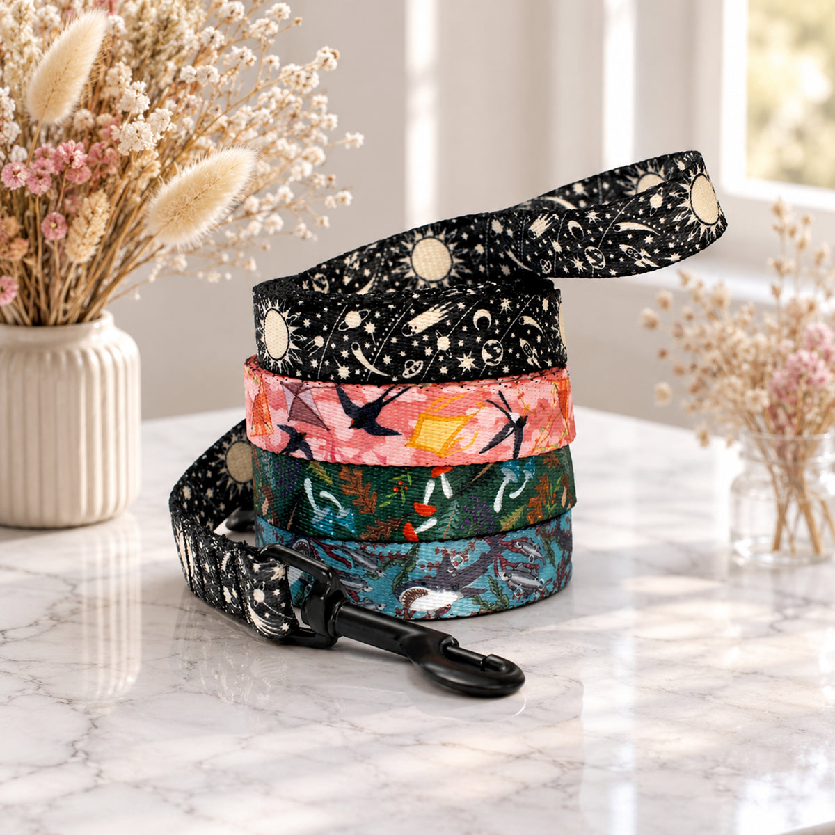 Stack of colorful dog leashes on a marble surface with decorative flowers in the background