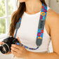 Person holding a camera with a colorful strap featuring donut designs.