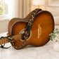 Acoustic guitar with a leopard print strap on a marble surface, with a blurred indoor background.