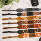 Collection of personalized camera straps with unique patterns and names on a marble surface.