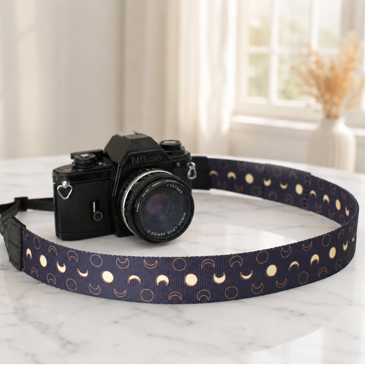Camera with a decorative strap on a marble surface