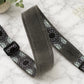 Gray guitar strap with patterned ends on a marble surface