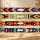 Four colorful patterned belts with 'STYLEZ' branding on a wooden surface.