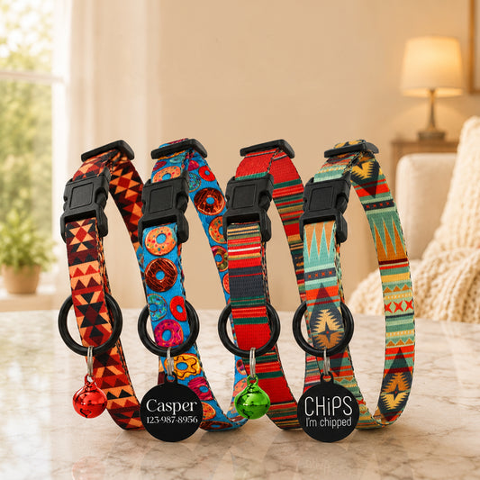 Four colorful dog collars with tags on a marble surface.
