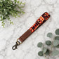 Patterned strap with brown leather end on a marble surface with green leaves.