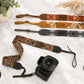 Camera with decorative camera strap on a light surface with plants