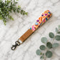 Colorful keychain strap with cupcake design on a marble surface with green leaves.