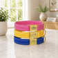 Three colorful dog collars with engraved names on a marble surface.