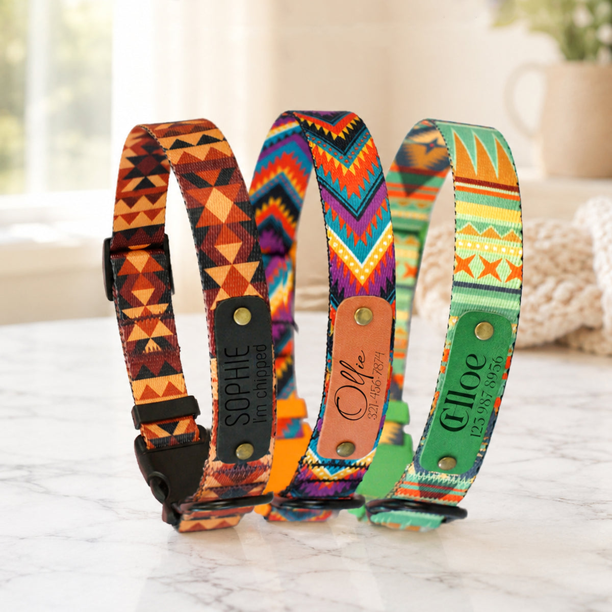 Three colorful dog collars with patterned designs on a marble surface.