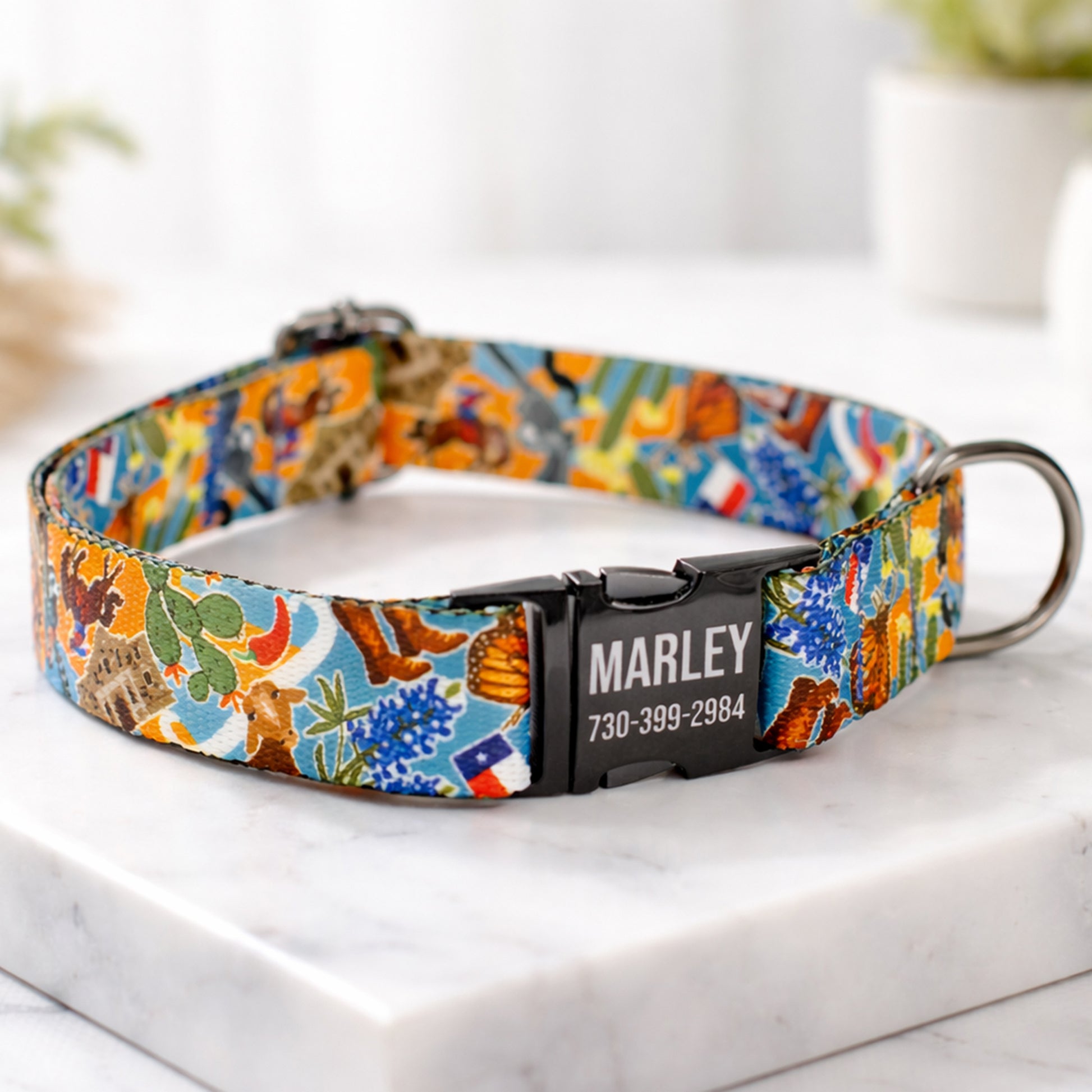 Colorful dog collar with a pattern and engraved nameplate on a marble surface