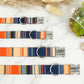 Set of colorful striped dog collars with engraved names on a marble surface.