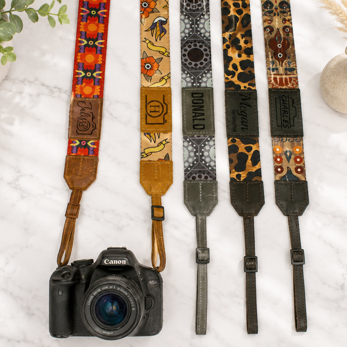 Collection of patterned camera straps with a Canon camera on a light background
