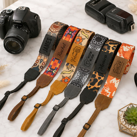 Collection of colorful camera straps with various patterns on a light surface, alongside a Canon camera and flash.