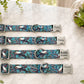 Four dog collars with engraved names on a marble surface.