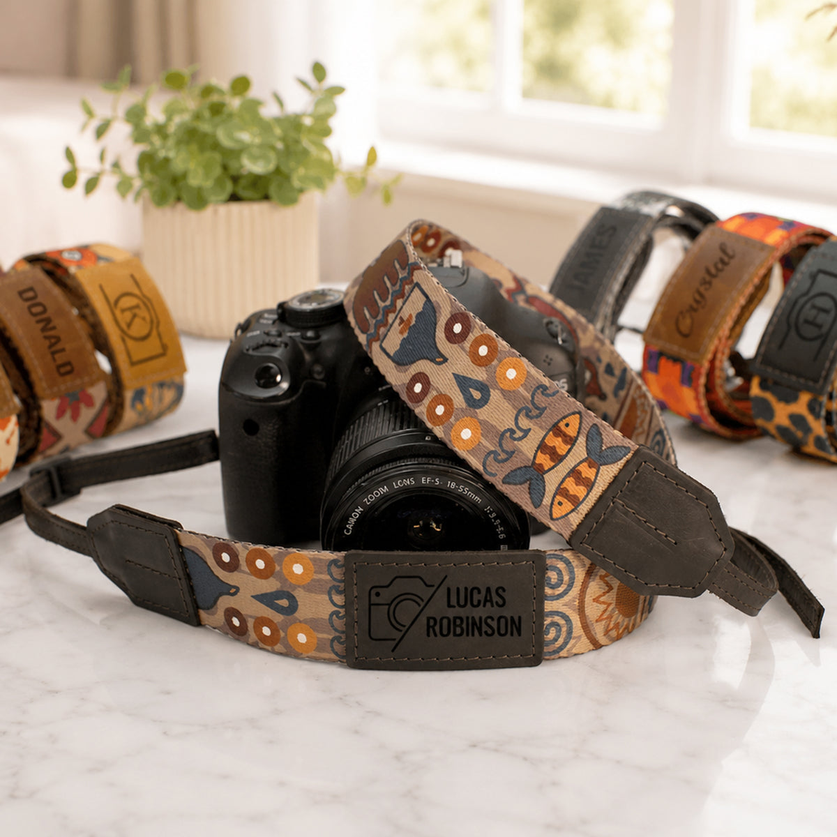 Camera with a patterned strap on a marble surface, with additional straps in the background.