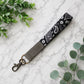 Keychain strap with paisley pattern on a marble surface with green leaves