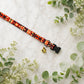 Decorative dog collar with geometric pattern and bell on a marble surface with greenery