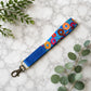 Colorful donut-patterned strap with blue end on a marble surface with green leaves.