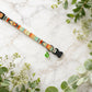 Colorful dog collar with floral design on a marble surface with greenery
