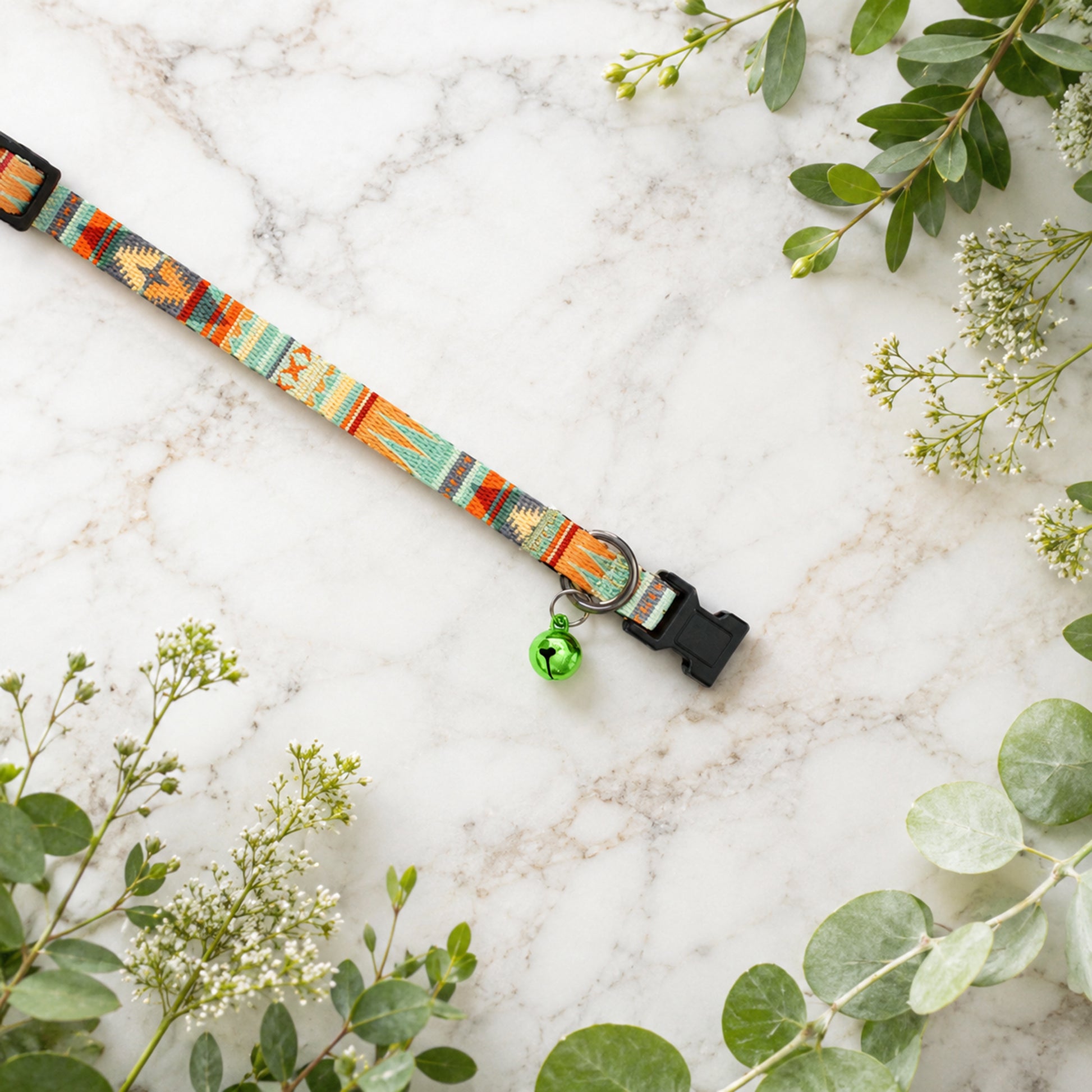 Colorful dog collar with floral design on a marble surface with greenery