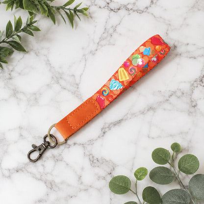 Colorful keychain strap with heart patterns on a marble surface with green leaves.