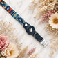 Navy blue dog collar with colorful pattern on a marble surface with flowers