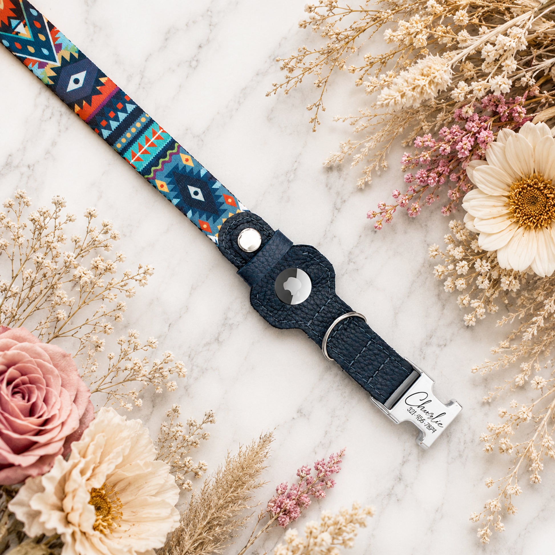 Navy blue dog collar with colorful pattern on a marble surface with flowers