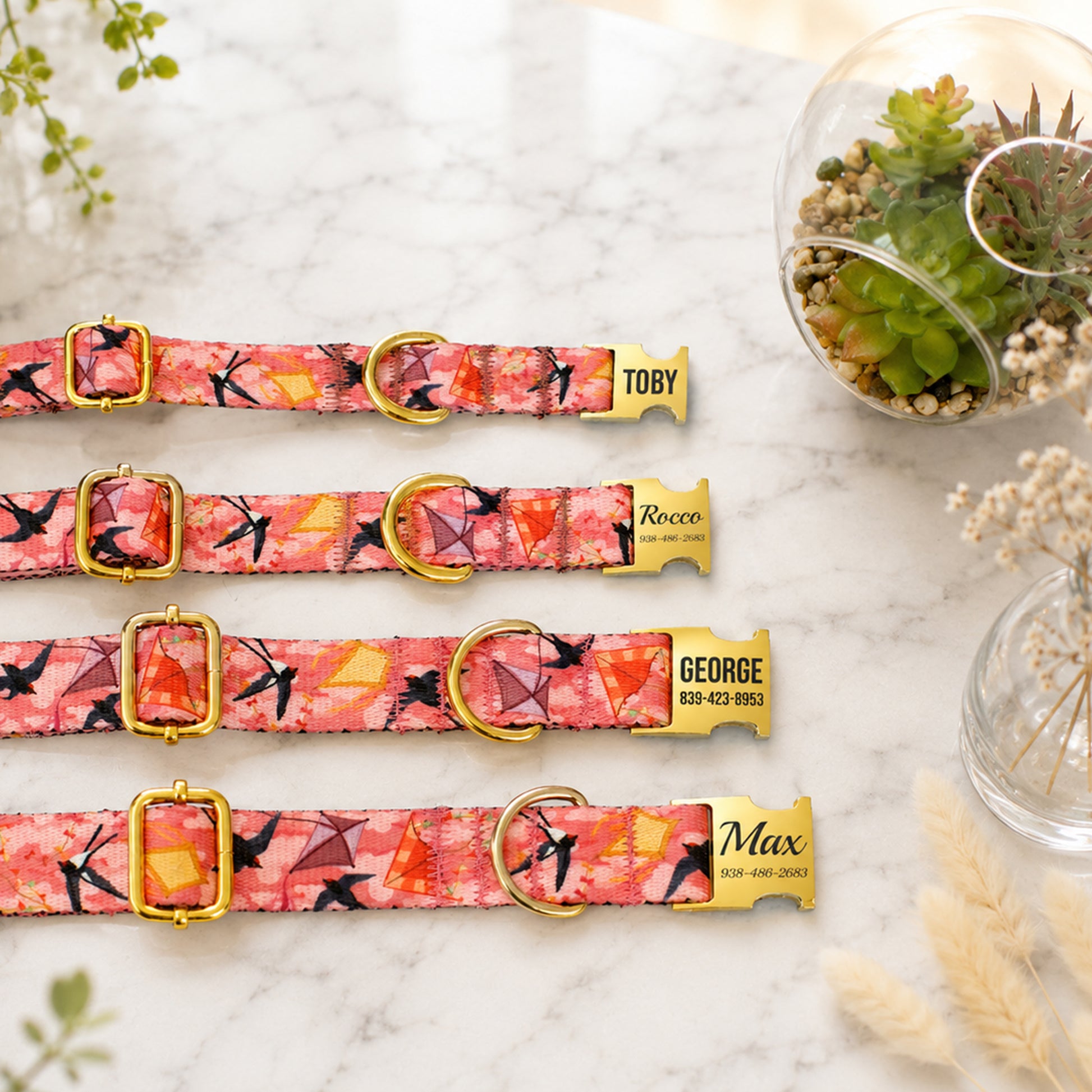 Set of three floral-patterned dog collars with gold buckles on a marble surface.