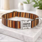 Striped dog collar with engraved nameplate on a marble surface