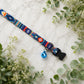 Colorful dog collar with a bell on a light background with greenery