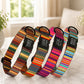 Four colorful striped dog collars with names on black tags on a marble surface.