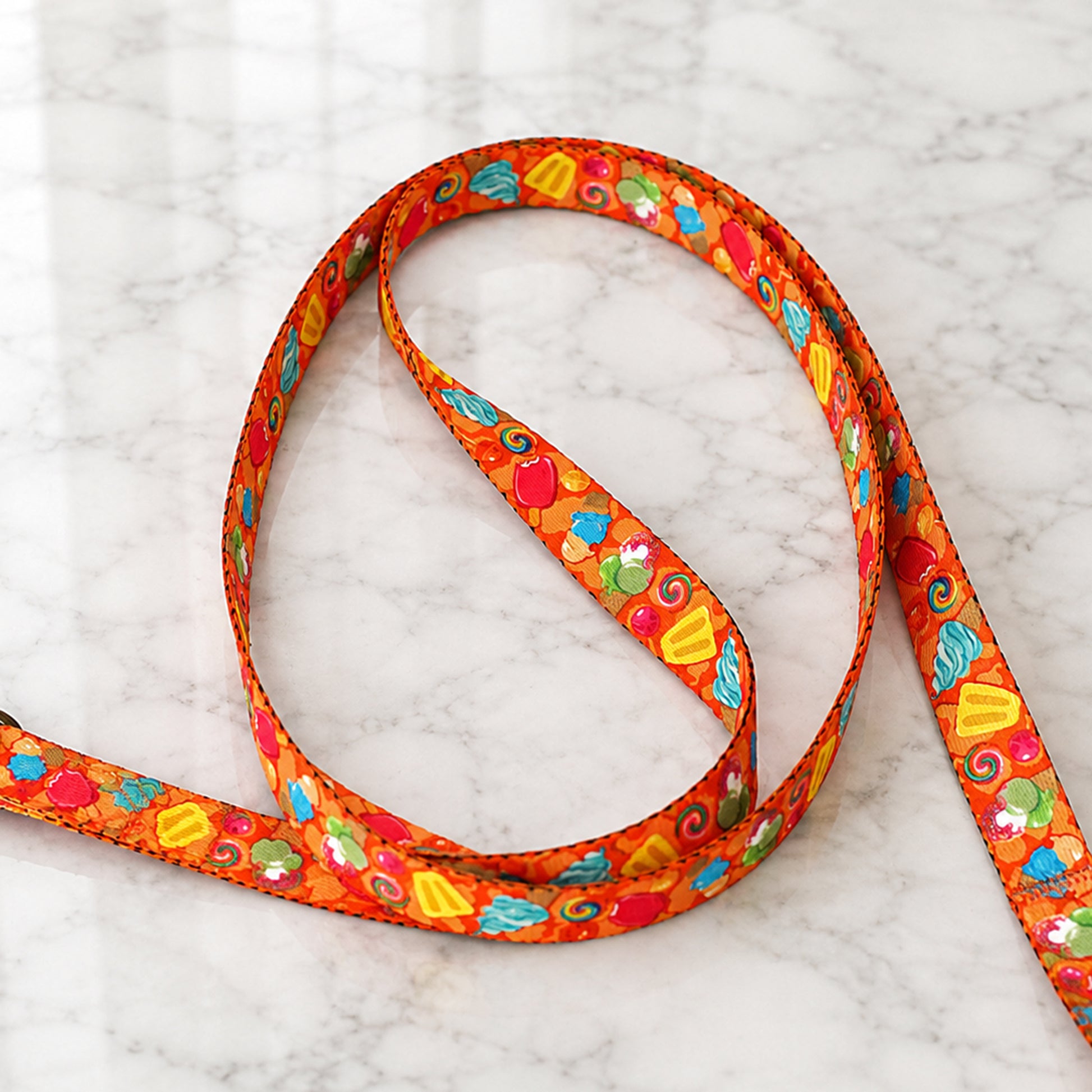 Colorful dog leash with candy-themed pattern on a marble surface