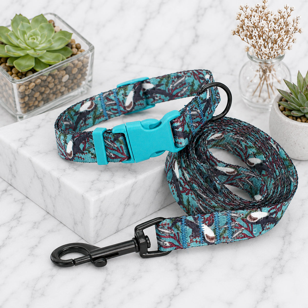Patterned dog collar and leash on a marble surface with decorative plants.