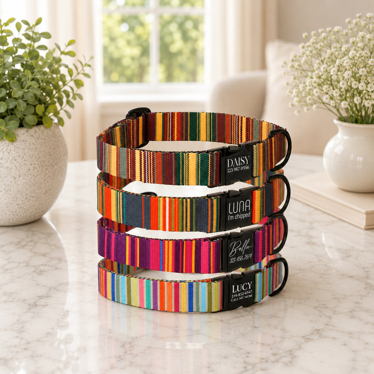 Stack of colorful striped dog collars on a marble surface with plants in the background