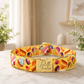 Colorful dog collar with a pattern of candies on a light surface.