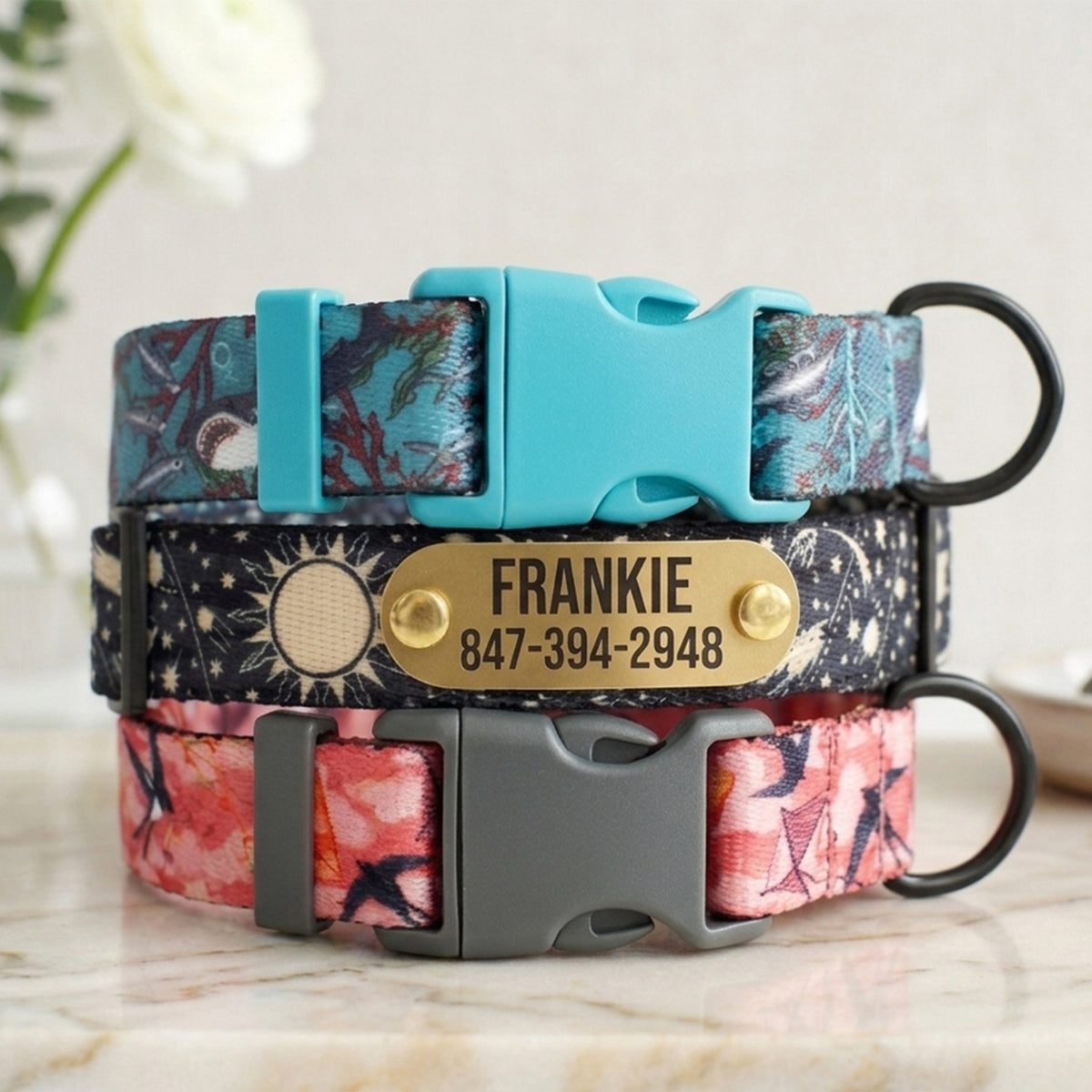 Two floral-patterned dog collars with nameplates on a light background