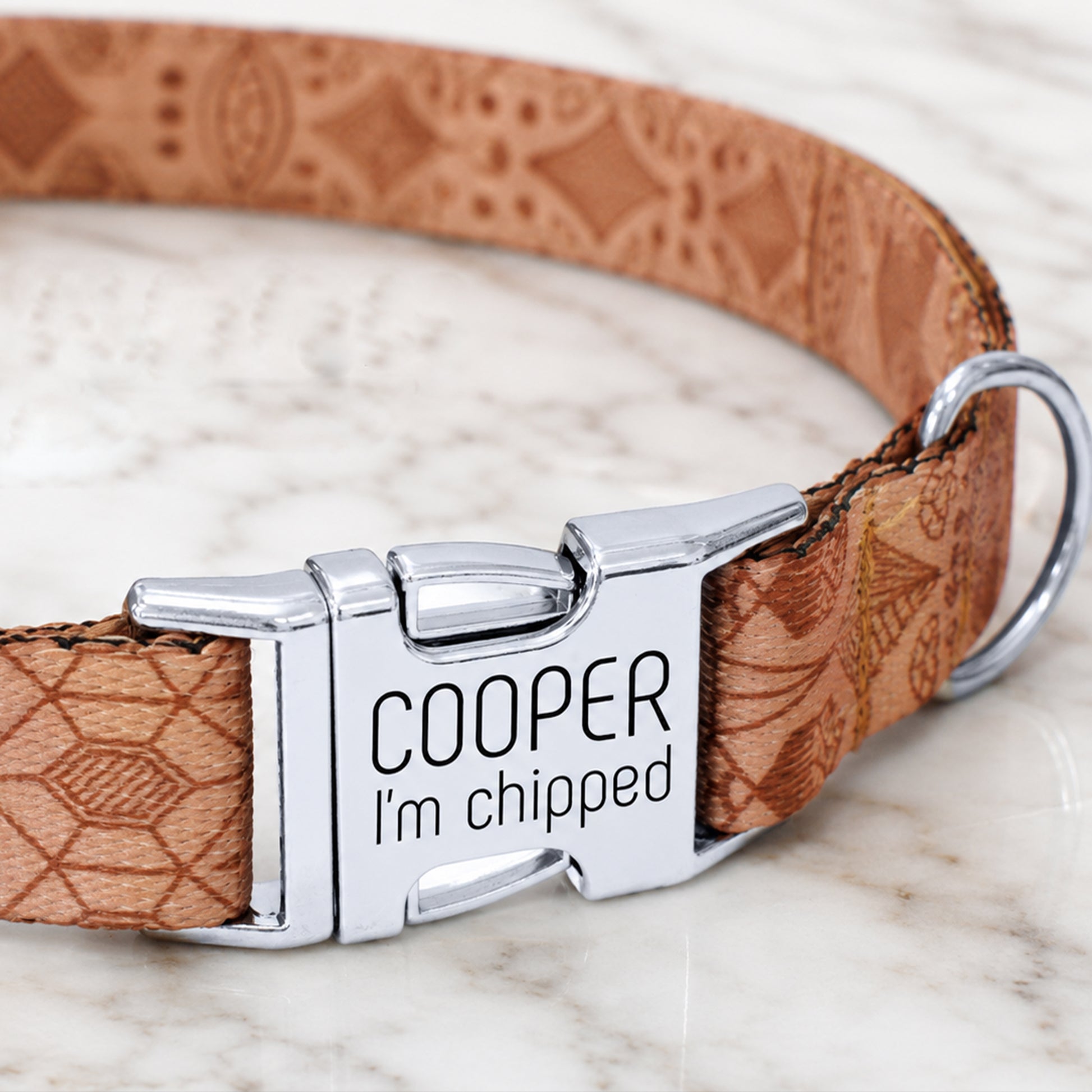 Dog collar with engraved metal tag on a marble surface