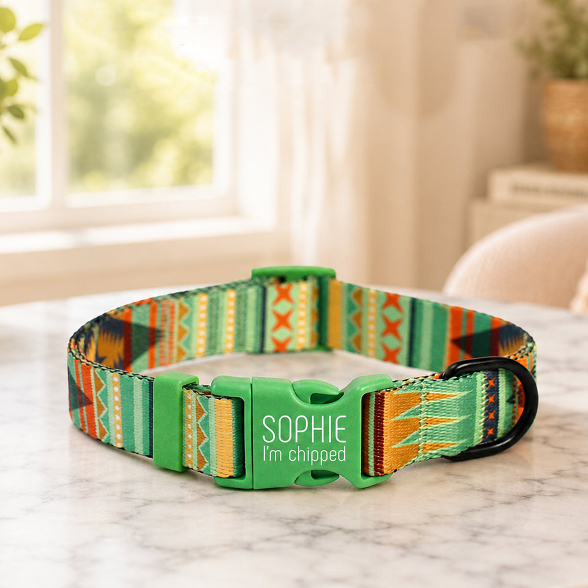 Green patterned dog collar with 'Sophie I'm chipped' text on a marble surface.